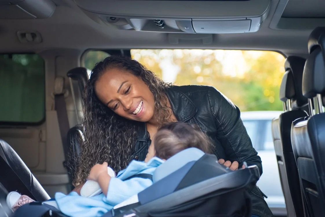 A mother helping her baby in a car seat